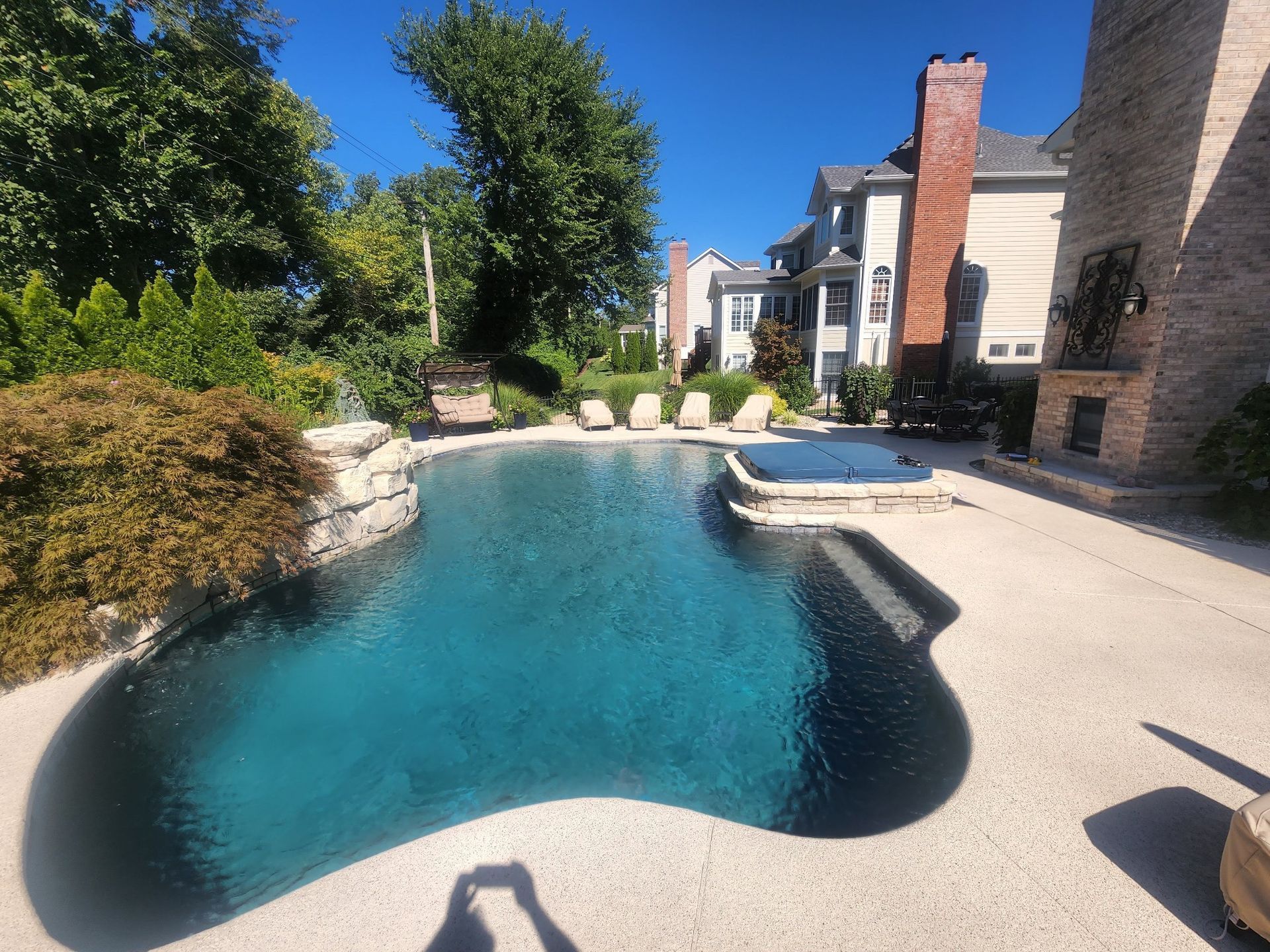 A pool with clear water next to trees and bushes