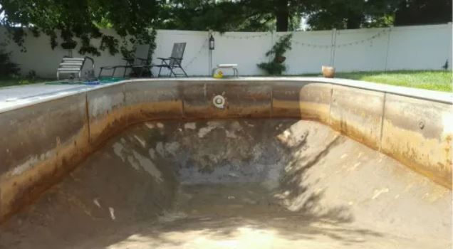 An empty swimming pool with a shed in the background