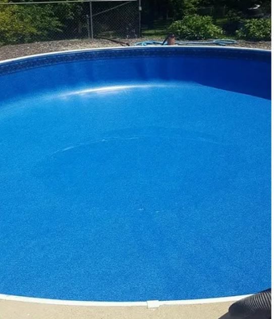 A large blue swimming pool with a fence in the background.