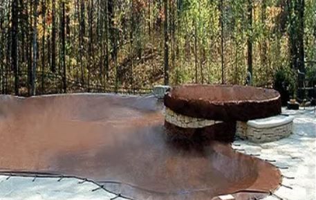 A swimming pool is covered with a brown cover.