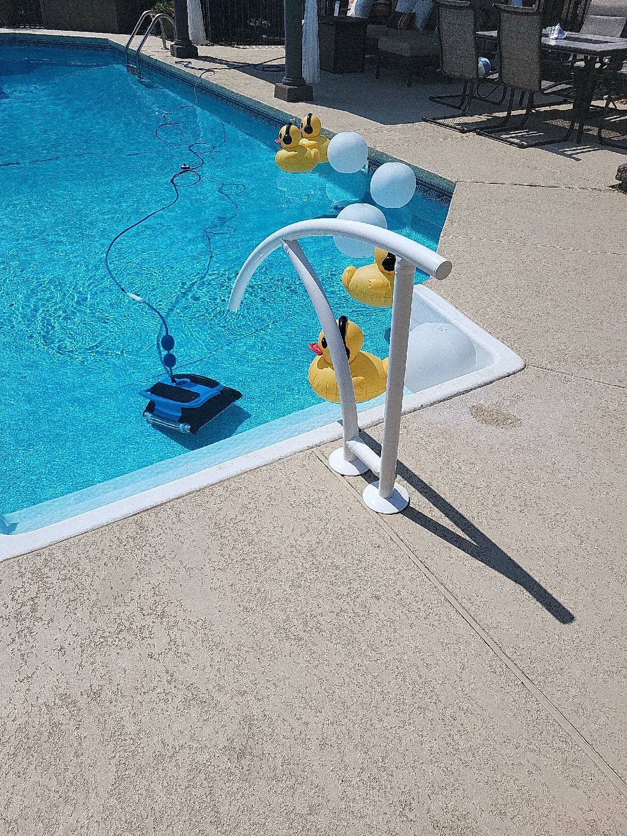 A pool with a robot cleaner and fake ducks