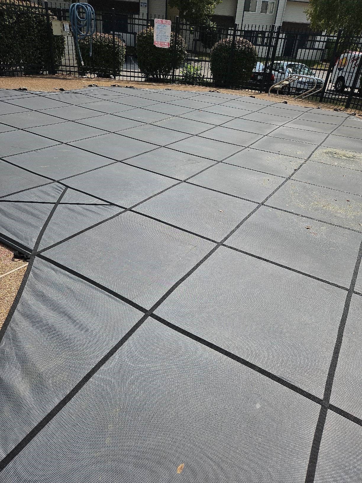 A pool with a grey mesh cover and a fence