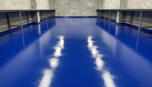 Blue industrial floor with white reflections beneath metal tables in a large room