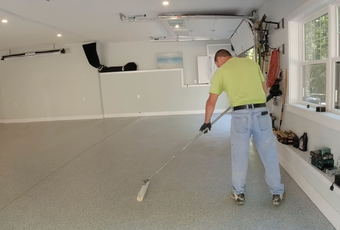 Epoxy flooring contractor applying a decorative coating system to a residential garage floor in Madison, Alabama.