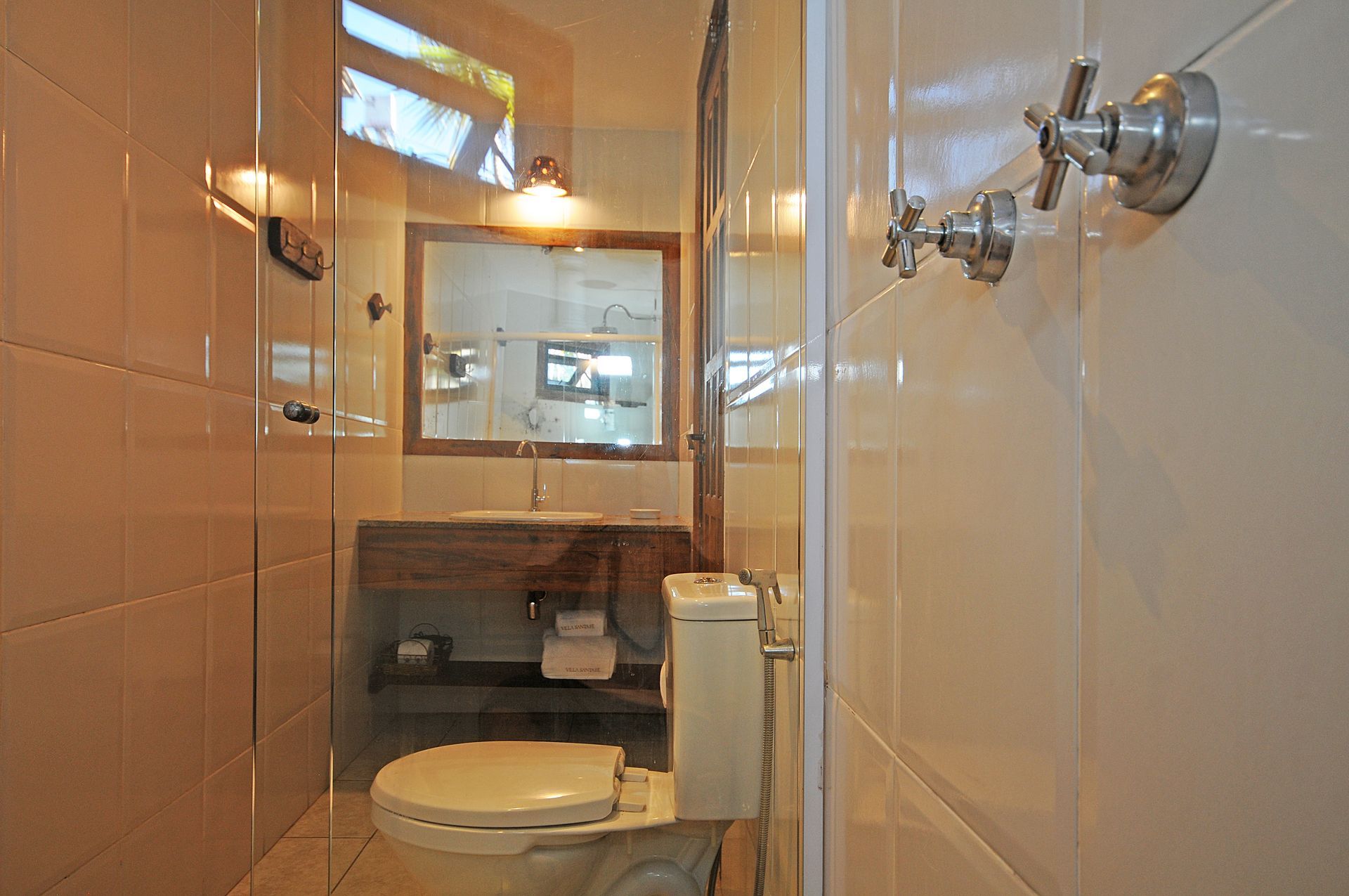 Small bathroom with white tiled walls, toilet, sink, and mirror.