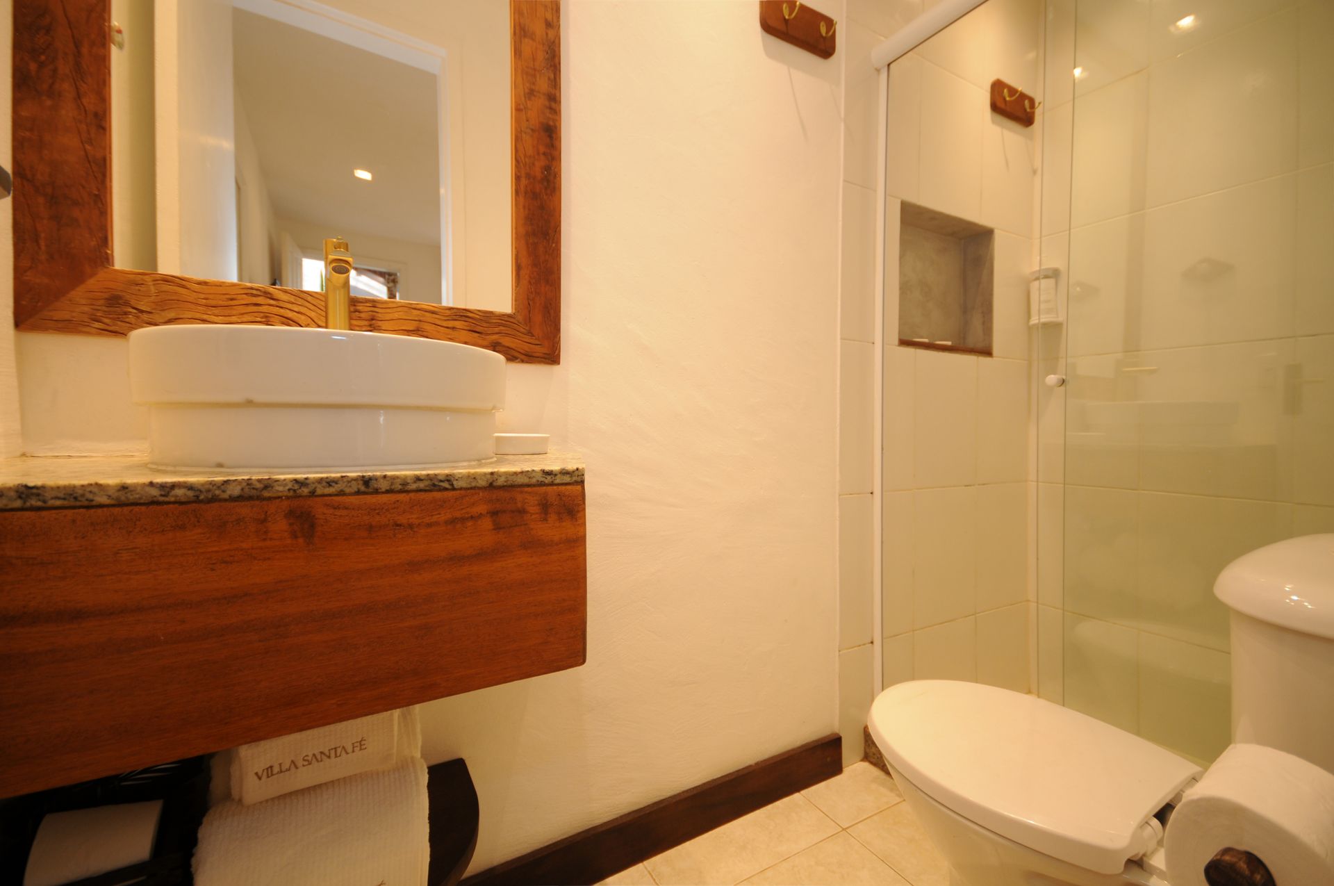 Bathroom with white walls, wooden vanity with vessel sink, and glass shower enclosure.