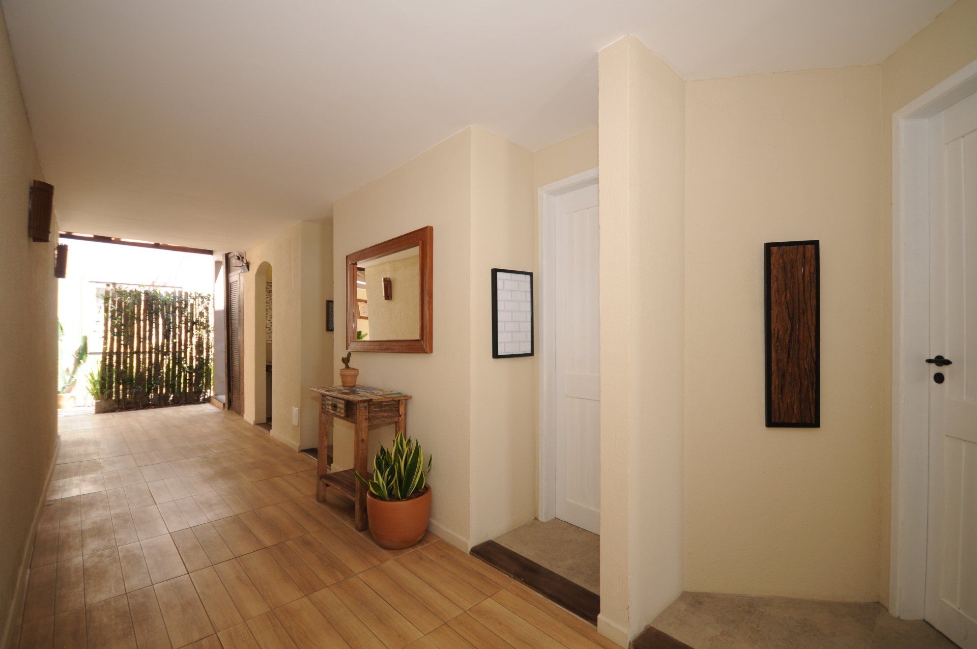Hallway with wooden floor, beige walls, and doorways leading to rooms.