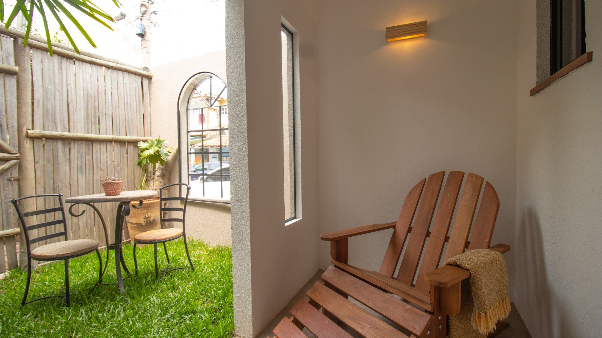 Wooden chair inside a small room, with a view of a small outdoor dining area with a table and chairs.