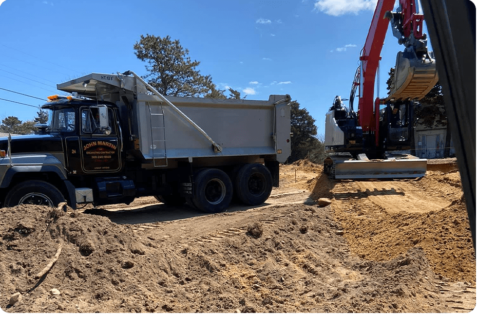 A dump truck being filled by an excavator at a construction site on a sunny day.