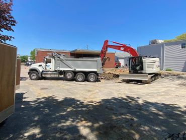 Excavator loading a dump truck with dirt at a construction site on a sunny day.