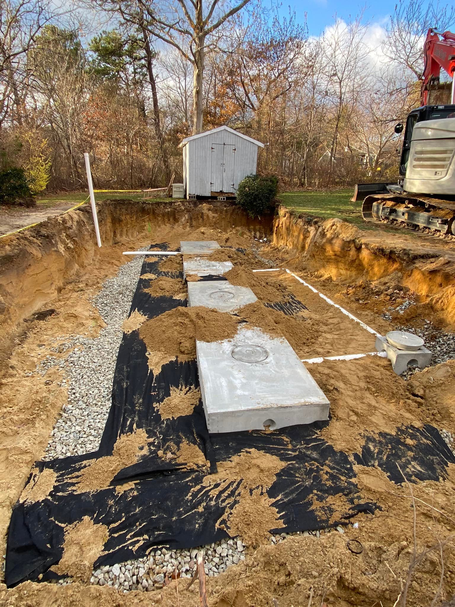 Septic system installation in progress: a deep excavation with concrete tanks, gravel, and machinery.