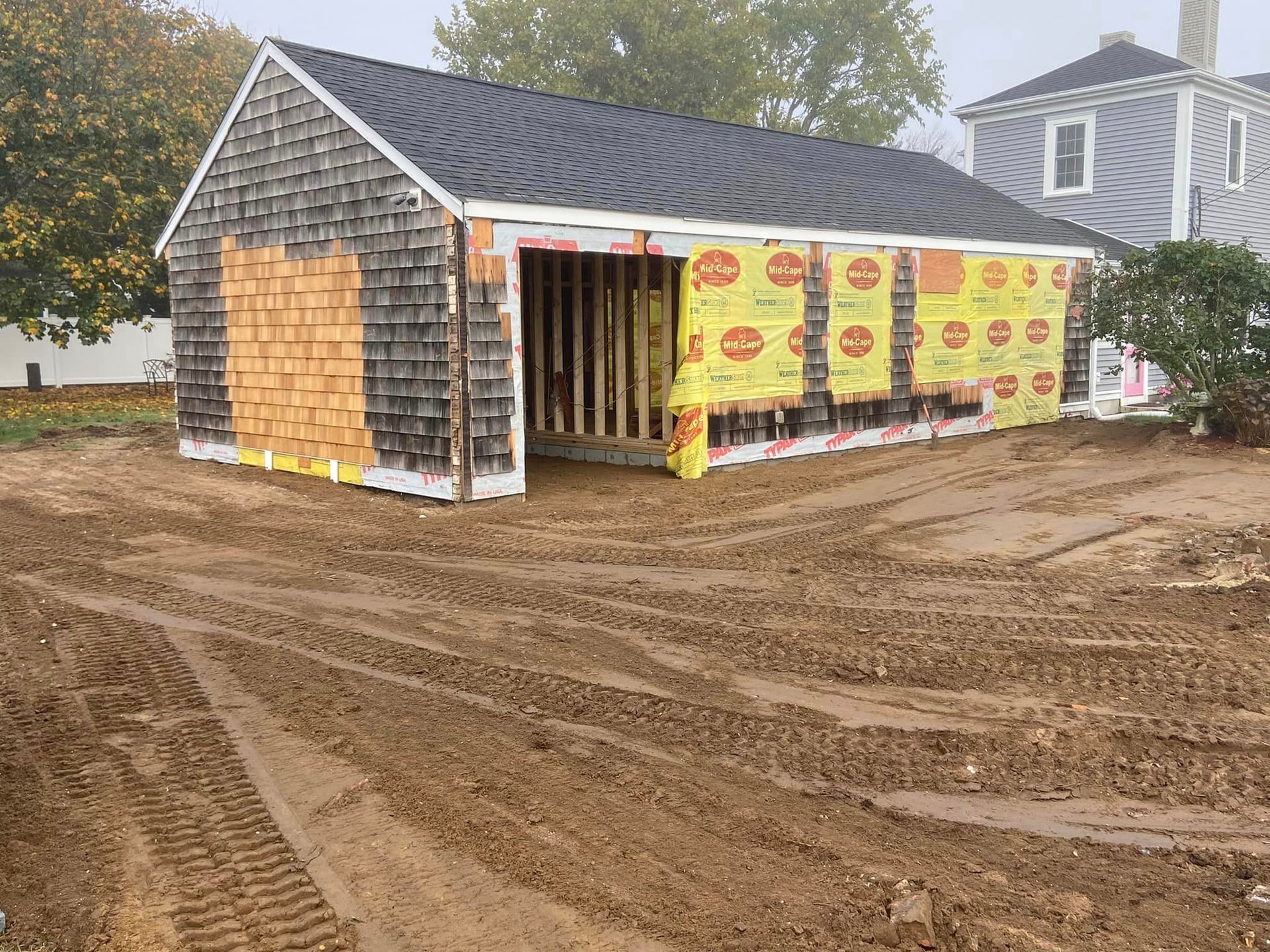 Garage under construction; wood frame, partially shingled, with yellow insulation visible.