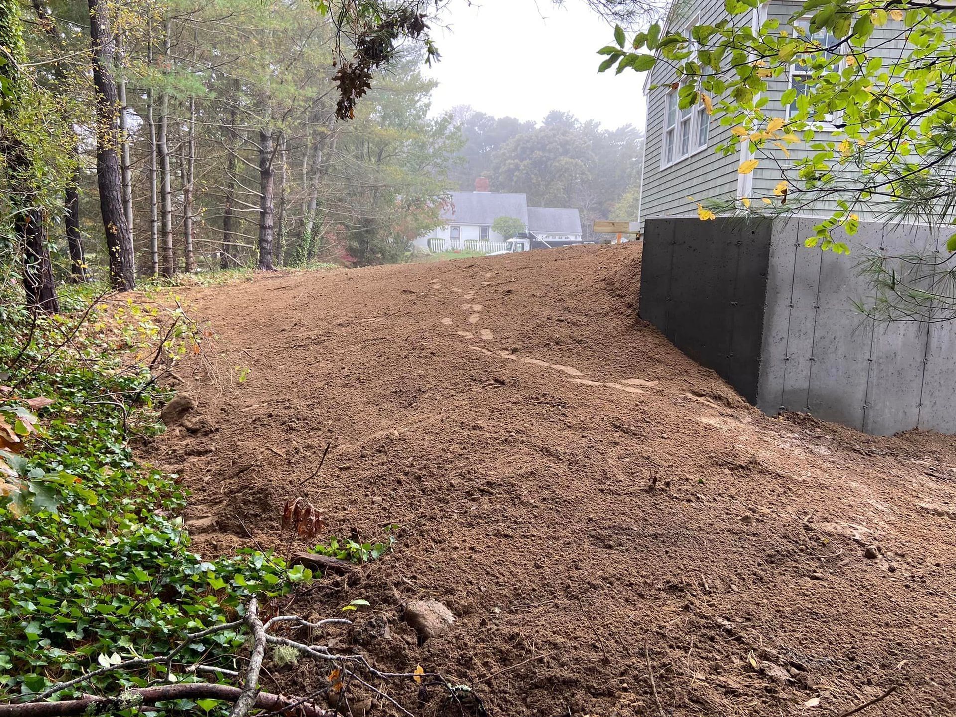Dirt pile next to a building, partially wooded. Brown earth dominates the scene.