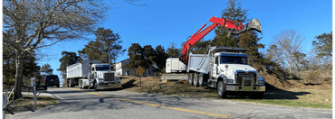 Two dump trucks being loaded by an excavator on a sunny day.