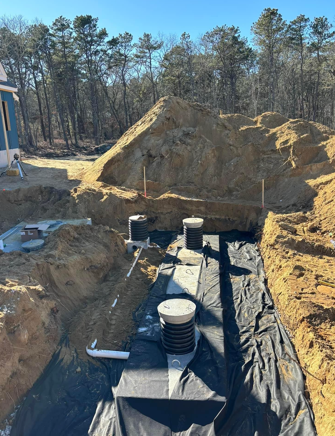 Excavated site for a septic system installation. Black fabric lines the trench, holding tanks and pipes.