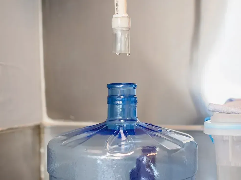 A bottle of water is sitting on a shelf next to a sink.