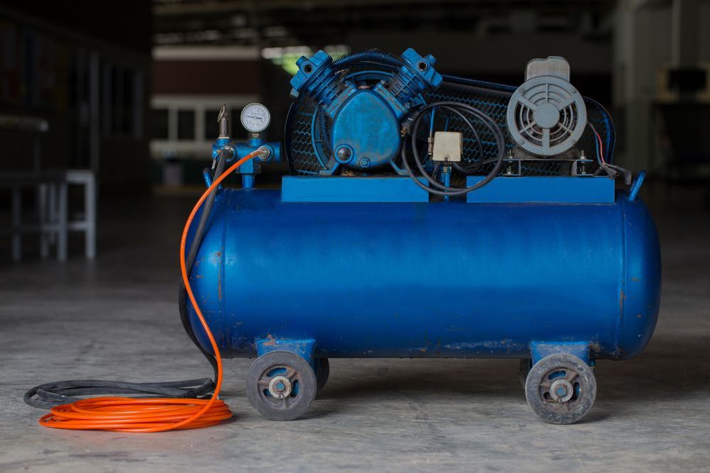 A Blue Air Compressor Is Sitting On The Floor In A Warehouse — Summerland Tool Supplies In Casino, NSW