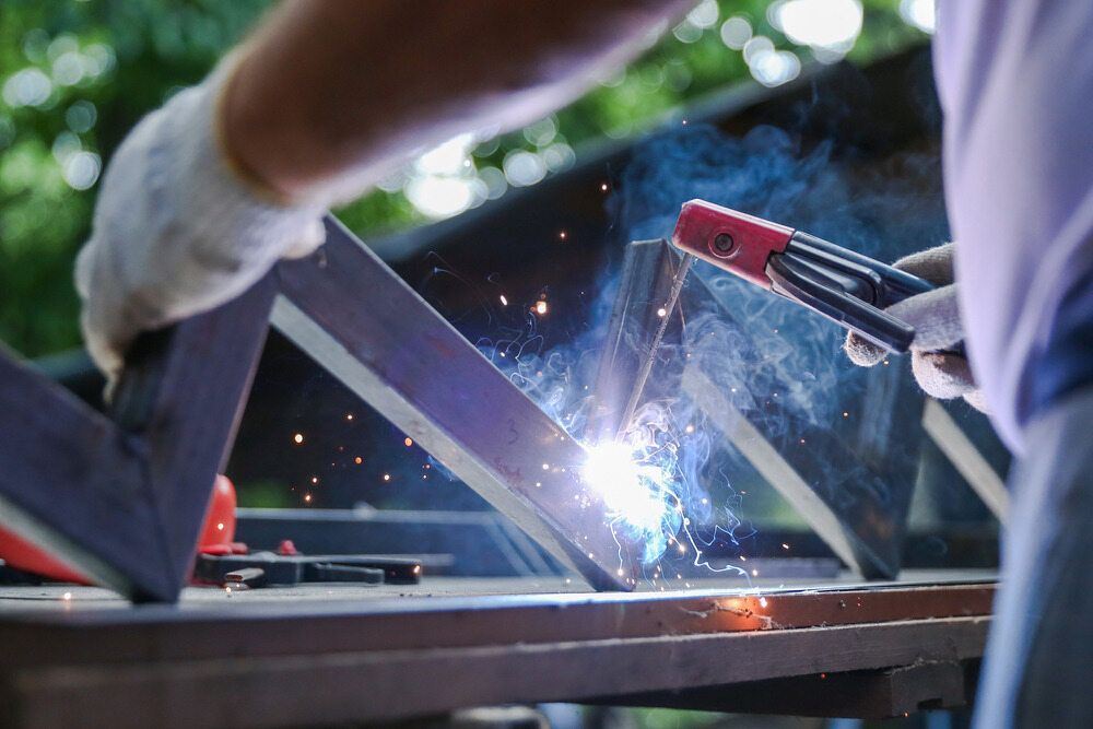 A Man Is Welding A Piece Of Metal On A Table — Summerland Tool Supplies In Casino, NSW
