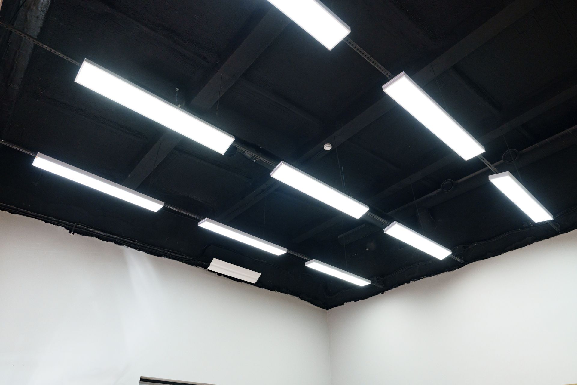 Modern ceiling lights illuminate a spacious room with black and white design.