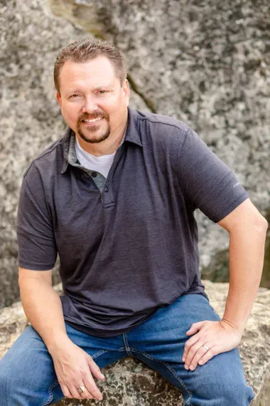 Shayne Webber posing against a large rock