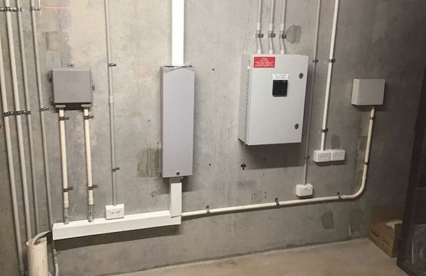 A room with a lot of wires hanging from the wall and a box on the wall.
