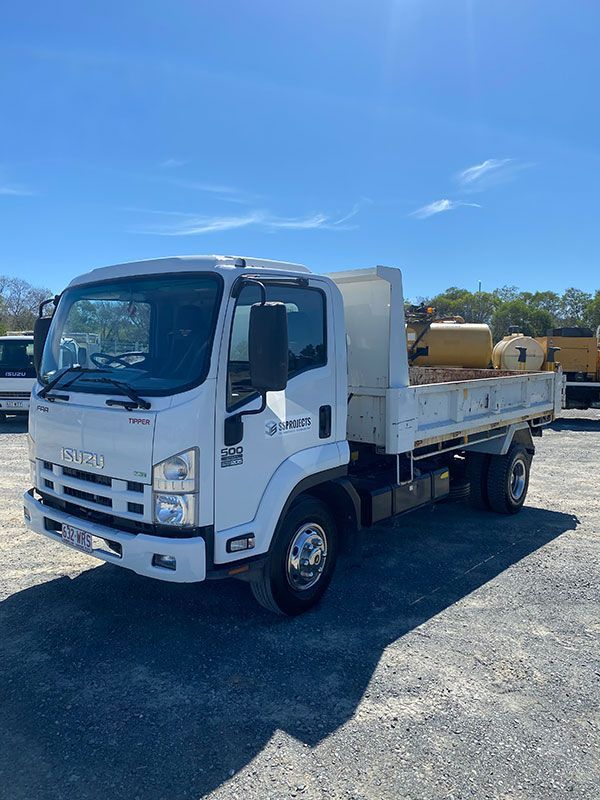 A white dump truck is parked in a parking lot.