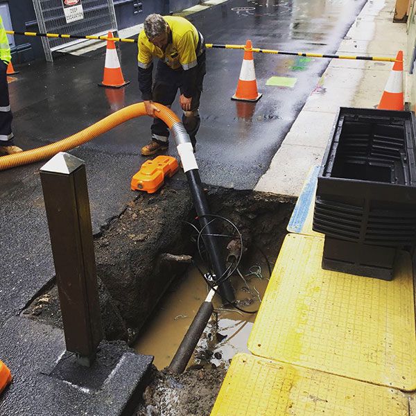 A man is working on a hole in the ground with a hose