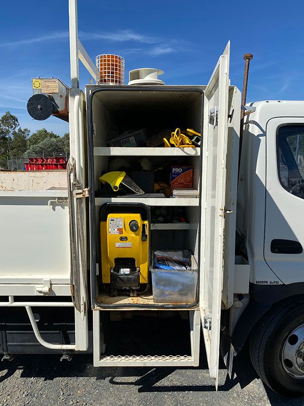 A white truck with the door open and tools in the back.