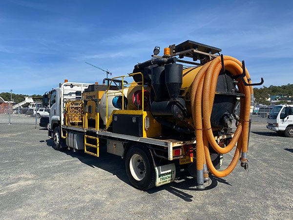 A yellow and black vacuum truck is parked in a parking lot.