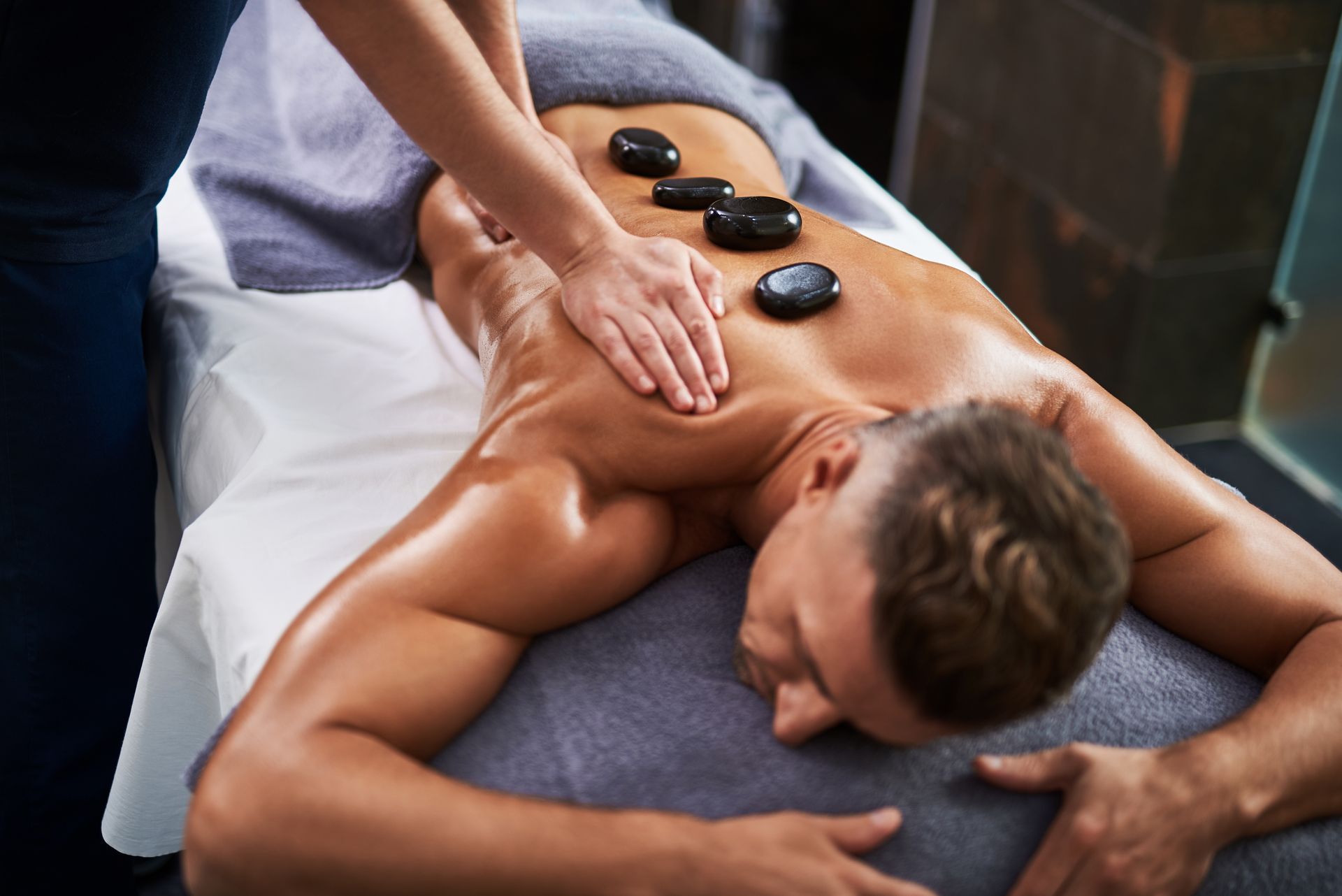 Person receiving a hot stone back massage on a spa table