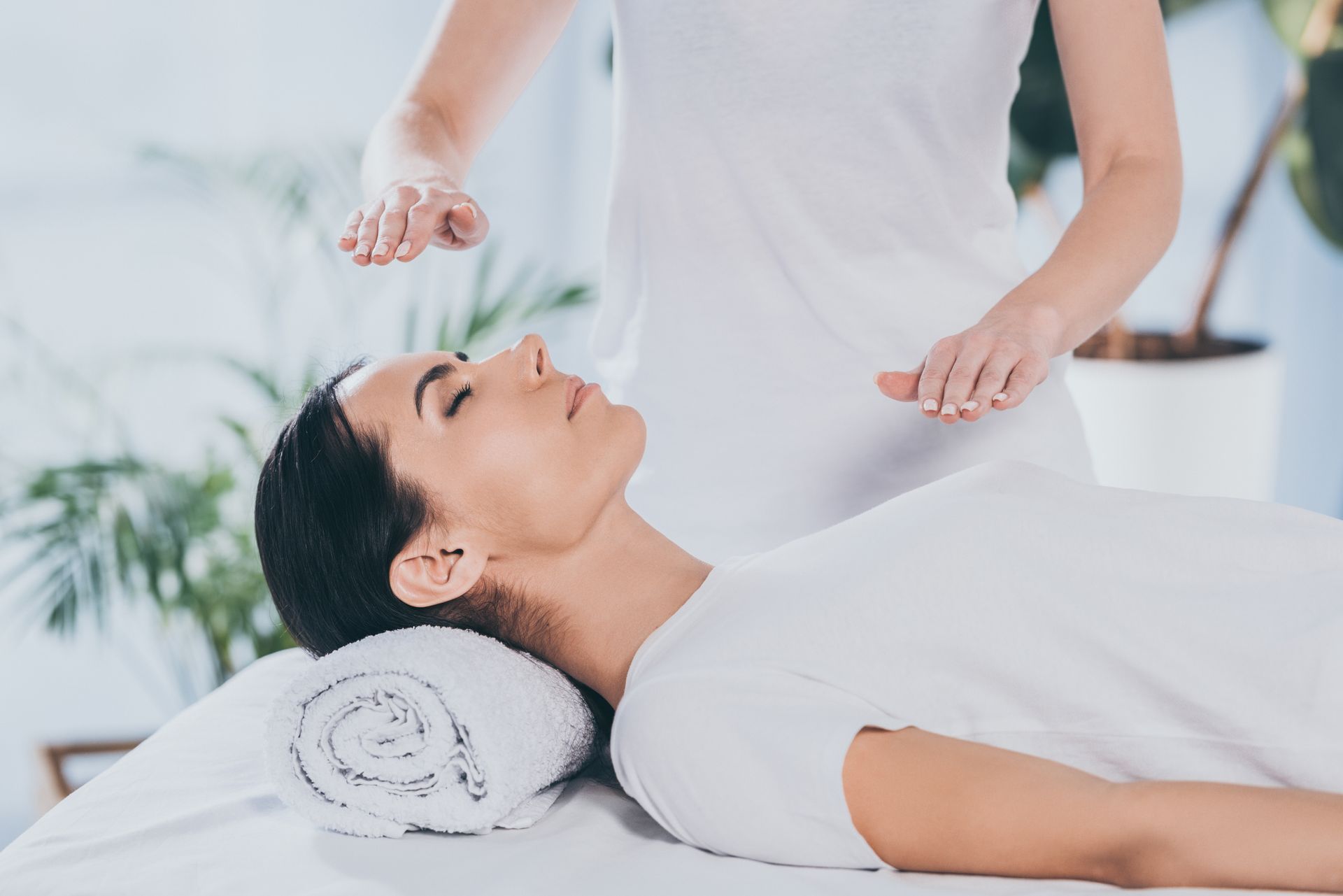 Hands massaging the sole of a foot on a white treatment table.
