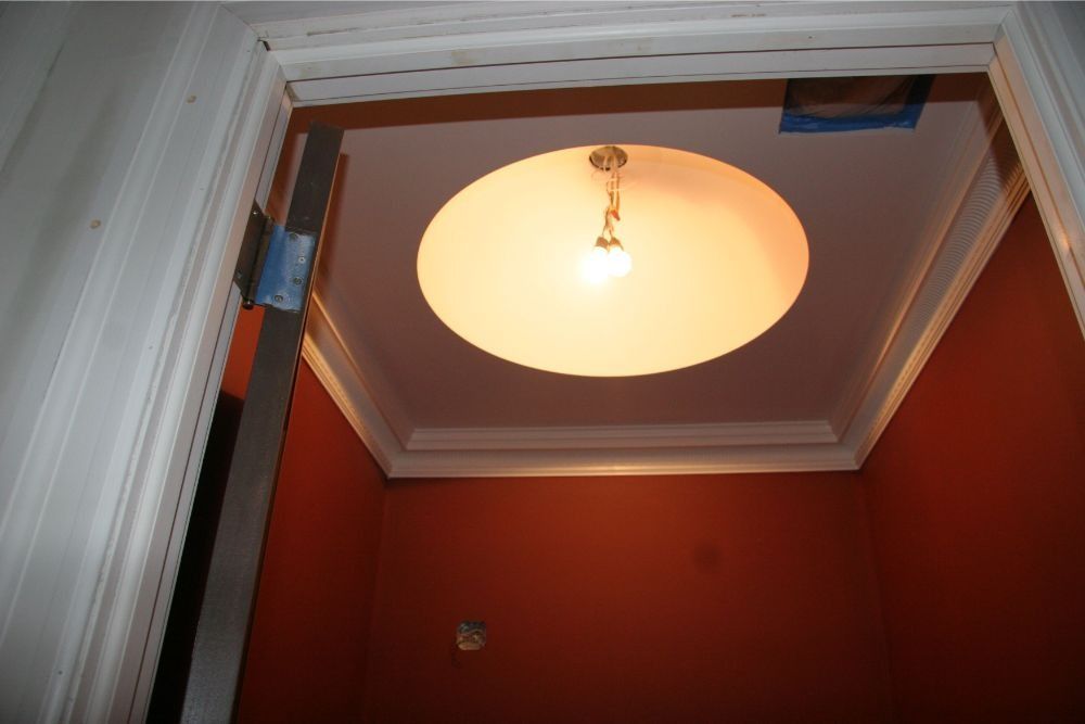 Red hallway ceiling with a round light fixture and open hatch framing the view upward