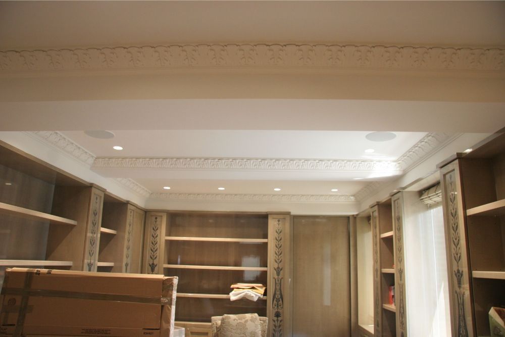Built-in wooden shelves in a bright room with ornate white ceiling moldings