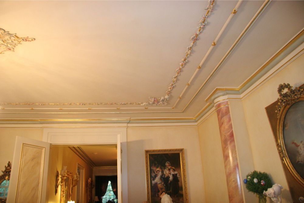 Ornate cream-and-gold ceiling and hallway interior with framed art and decorative molding
