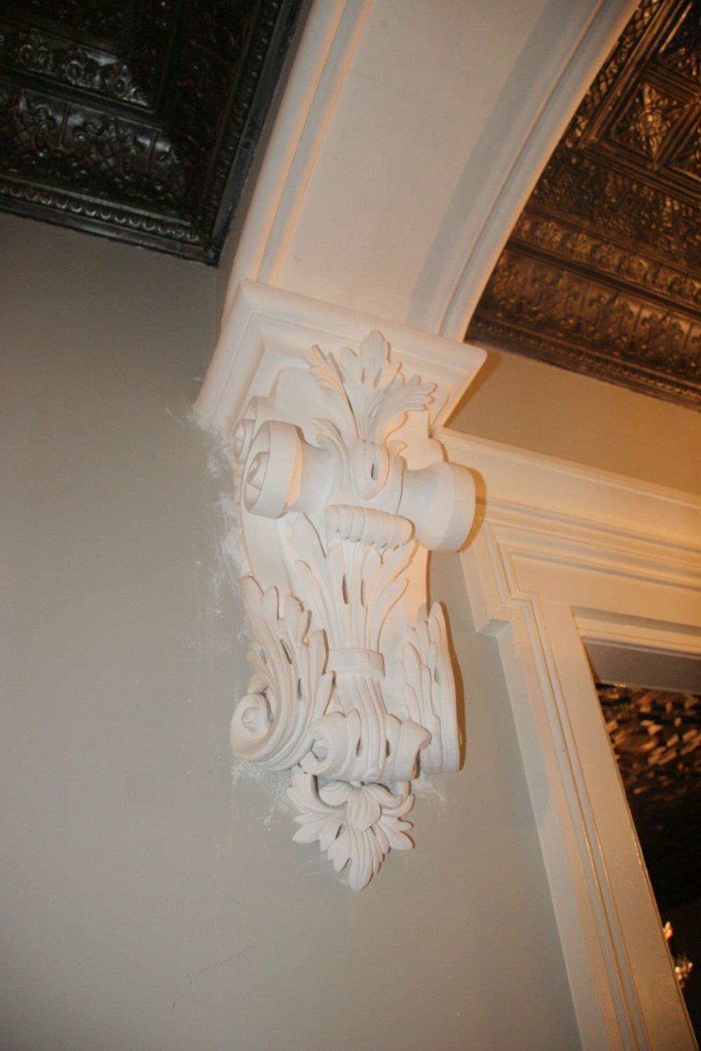 Ornate white carved corbel supporting a ceiling arch in an interior room