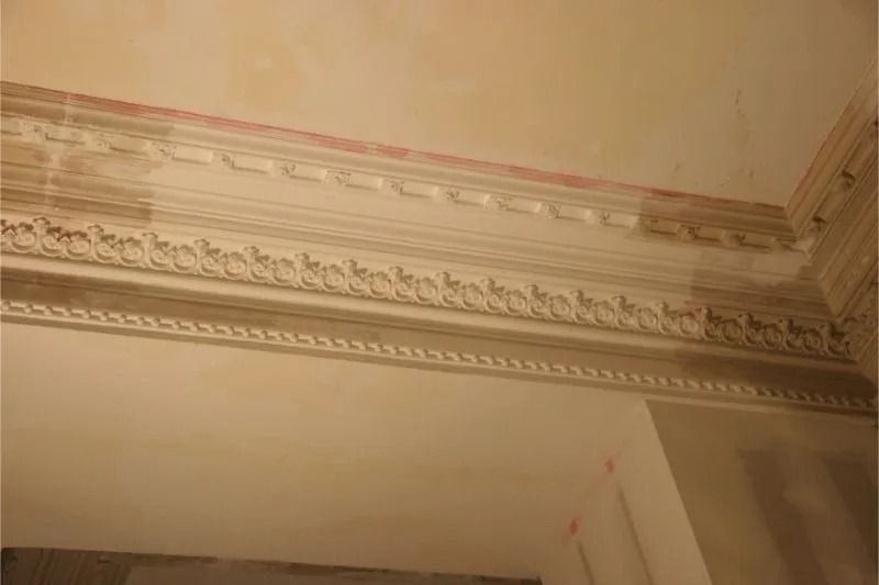Decorative white crown molding with floral trim along a cream-colored ceiling corner