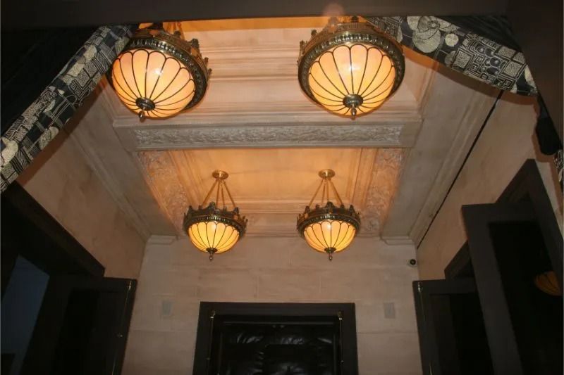 Ornate hallway ceiling with four warm-lit hanging lanterns and decorative molding