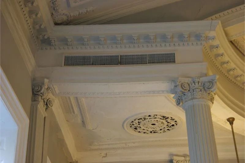 Ornate white interior ceiling with decorative columns, molding, and a round medallion.
