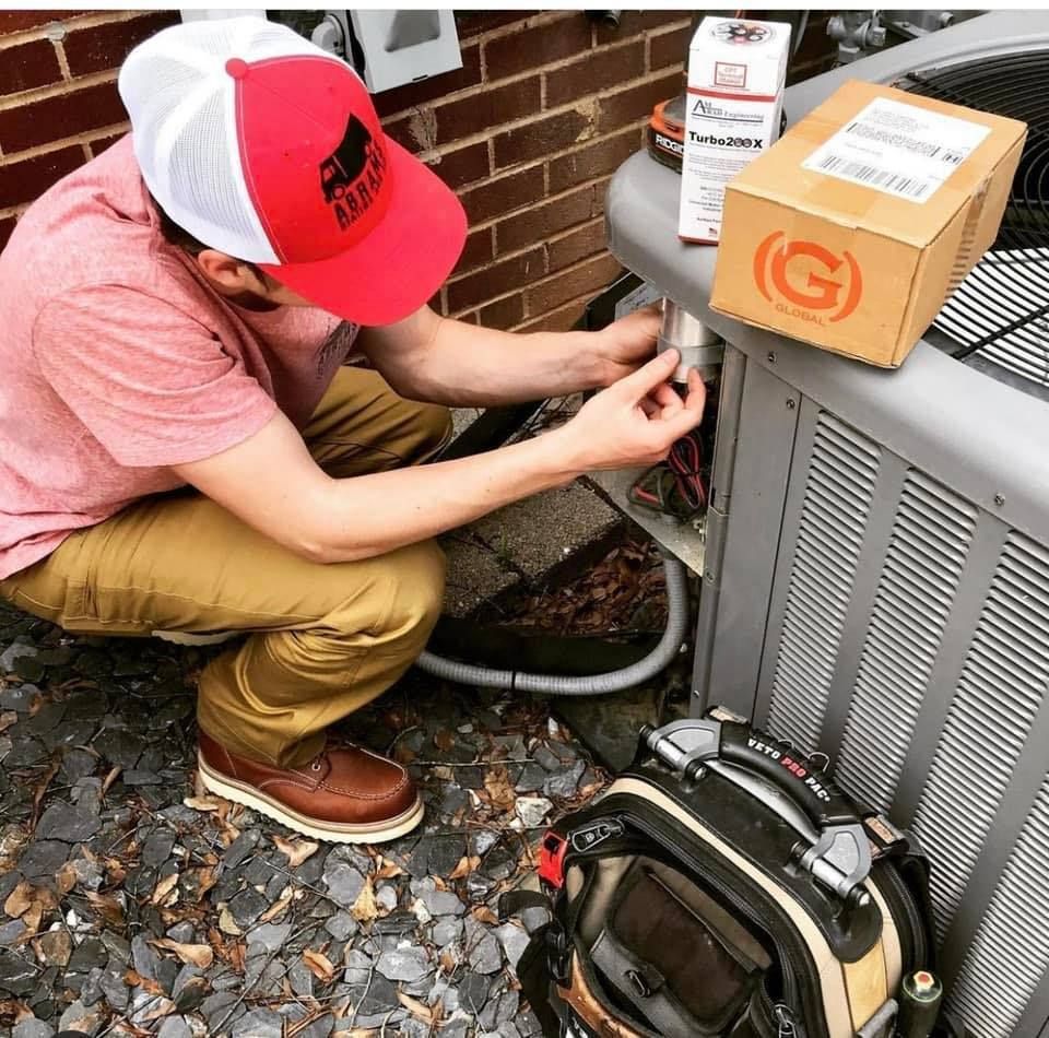 A man in a red hat is working on an air conditioner