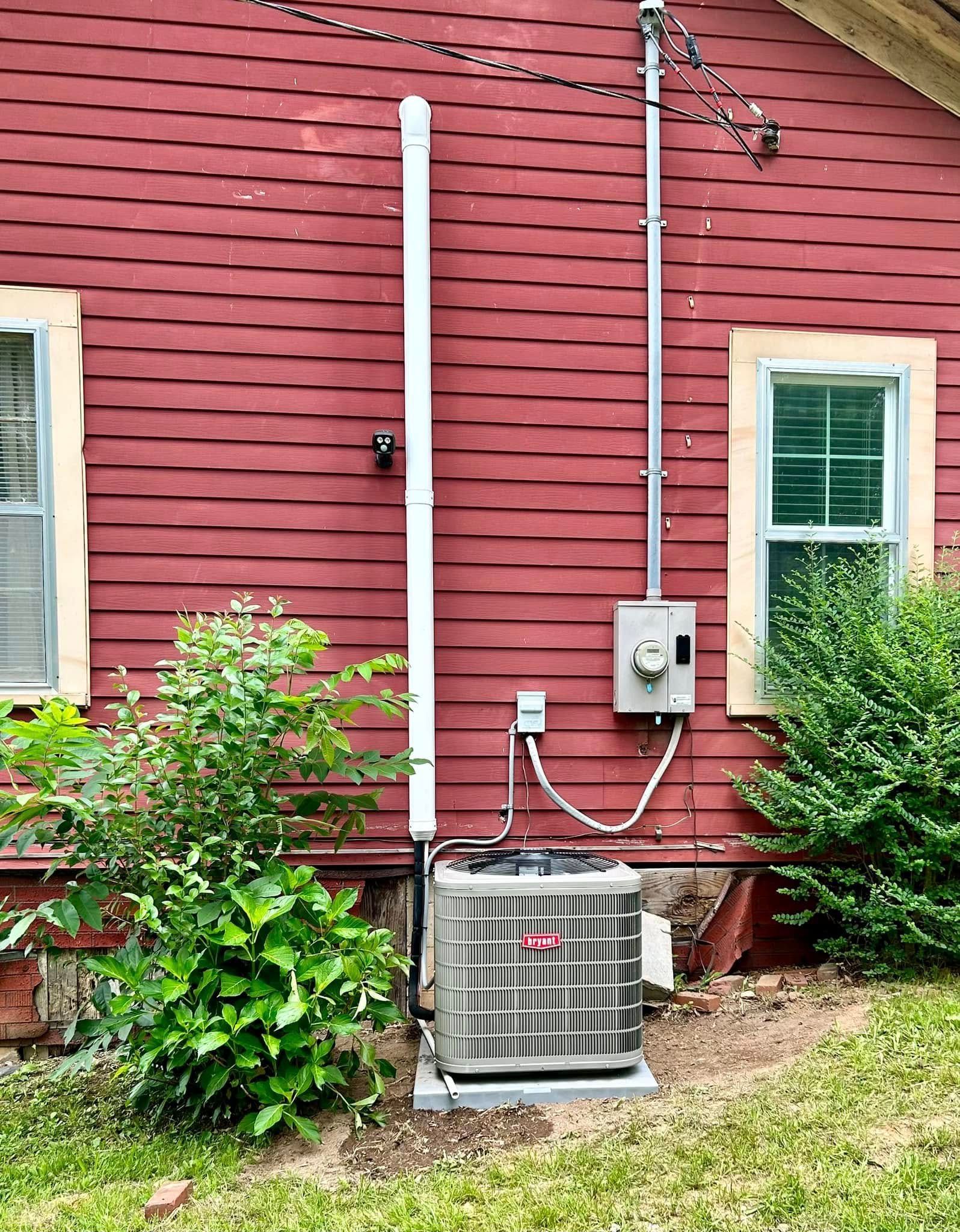 A red house with a air conditioner on the side of it.