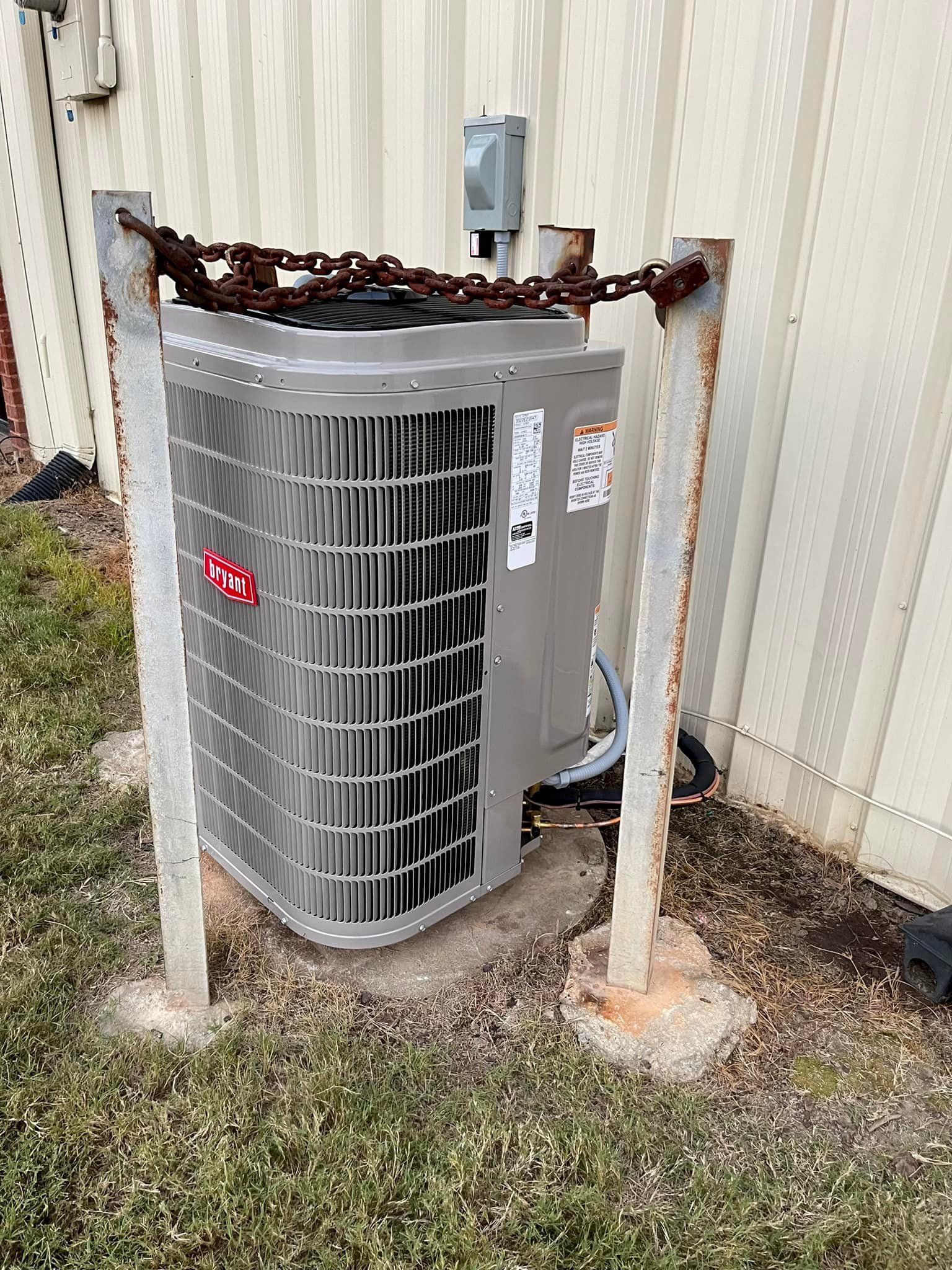An air conditioner is sitting on the ground next to a building.