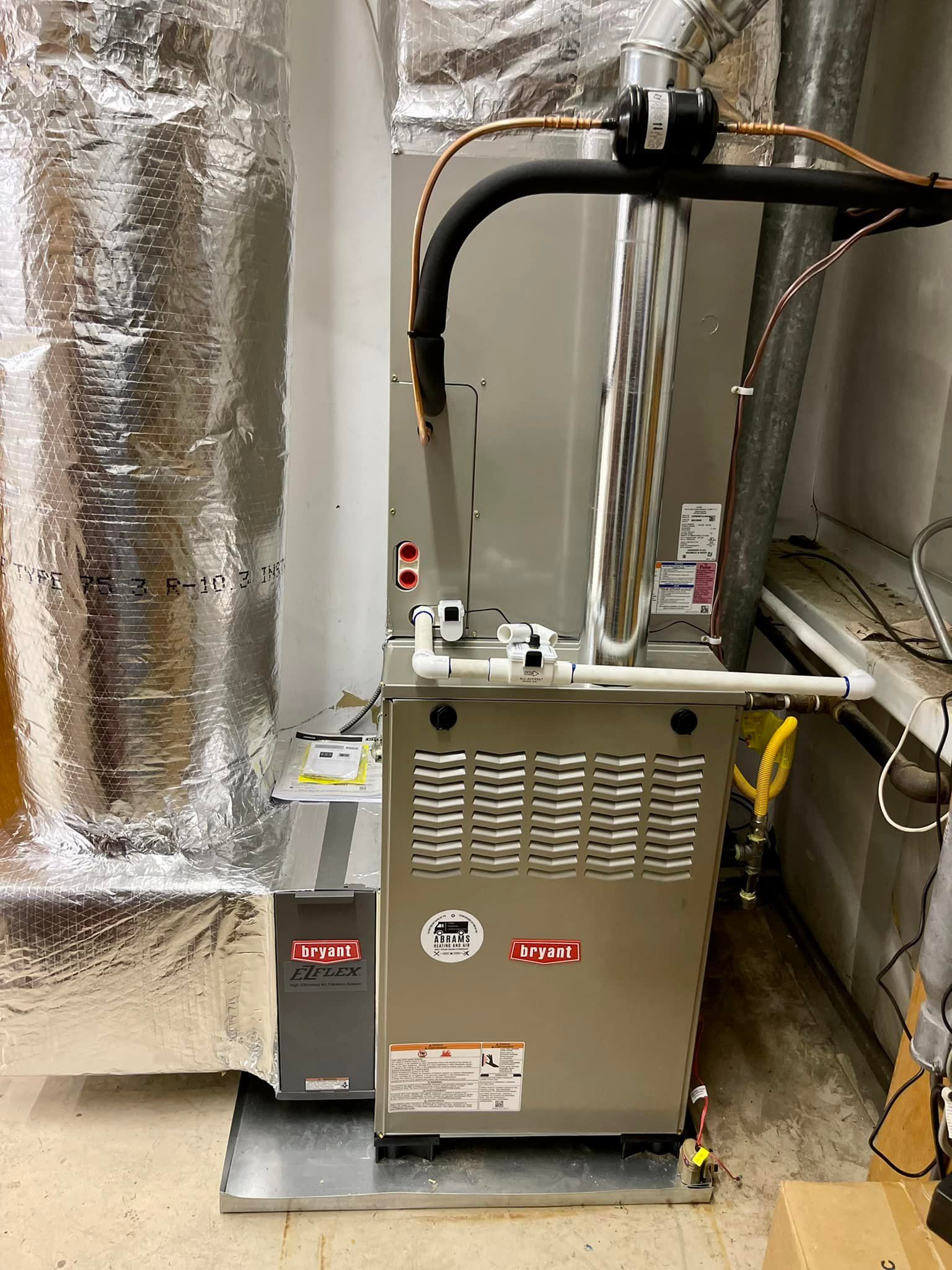 A furnace is sitting in a corner of a room next to a wall.