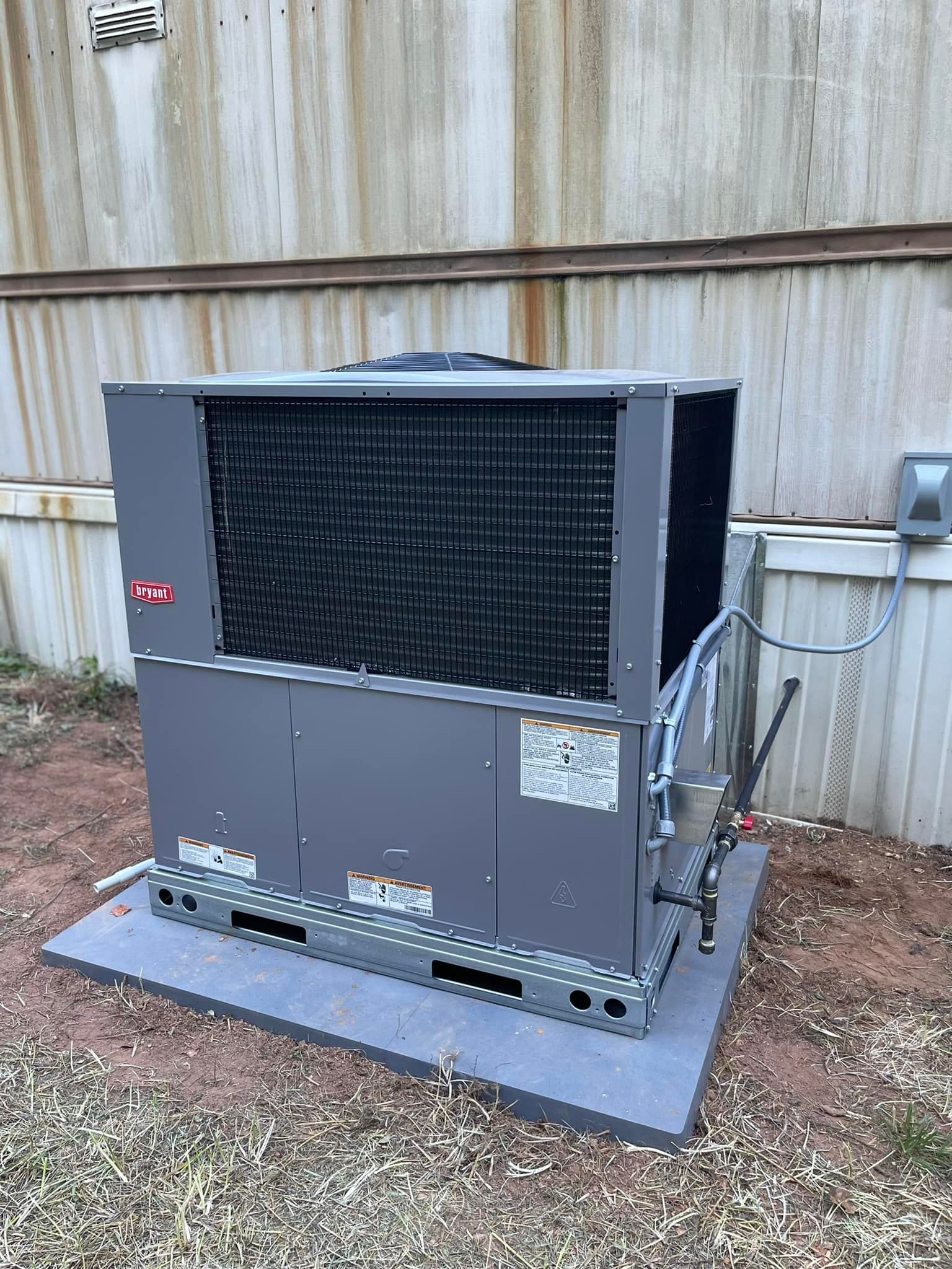 A large air conditioner is sitting on top of a concrete platform in front of a building.