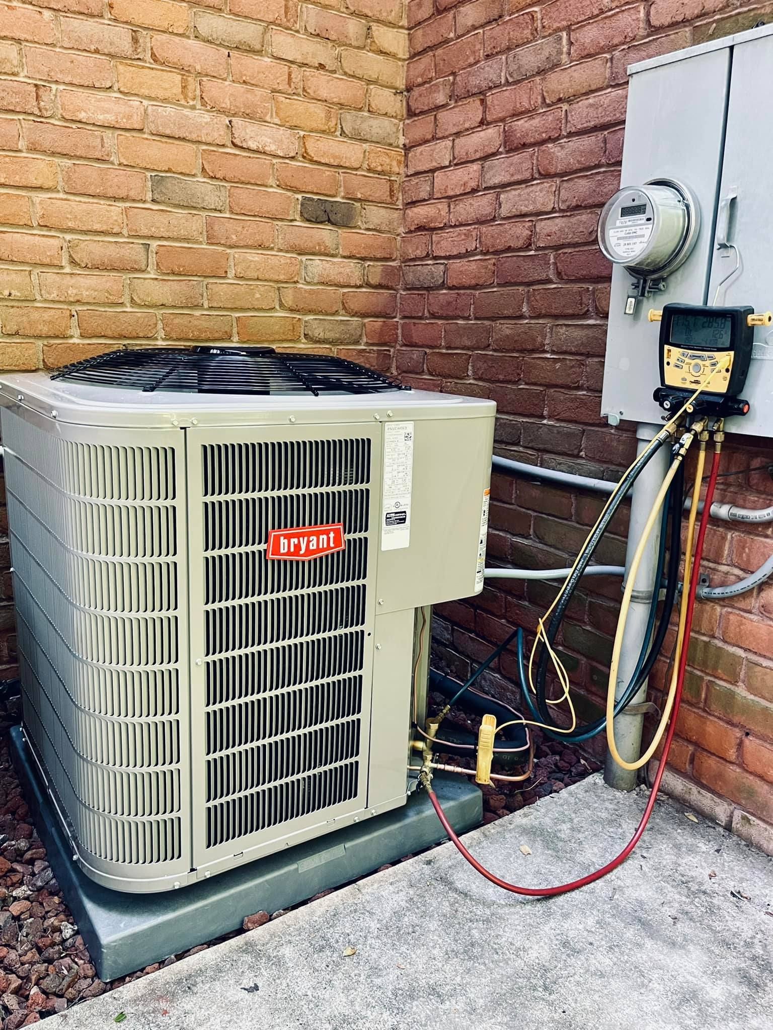 A large air conditioner is sitting on the side of a brick building.