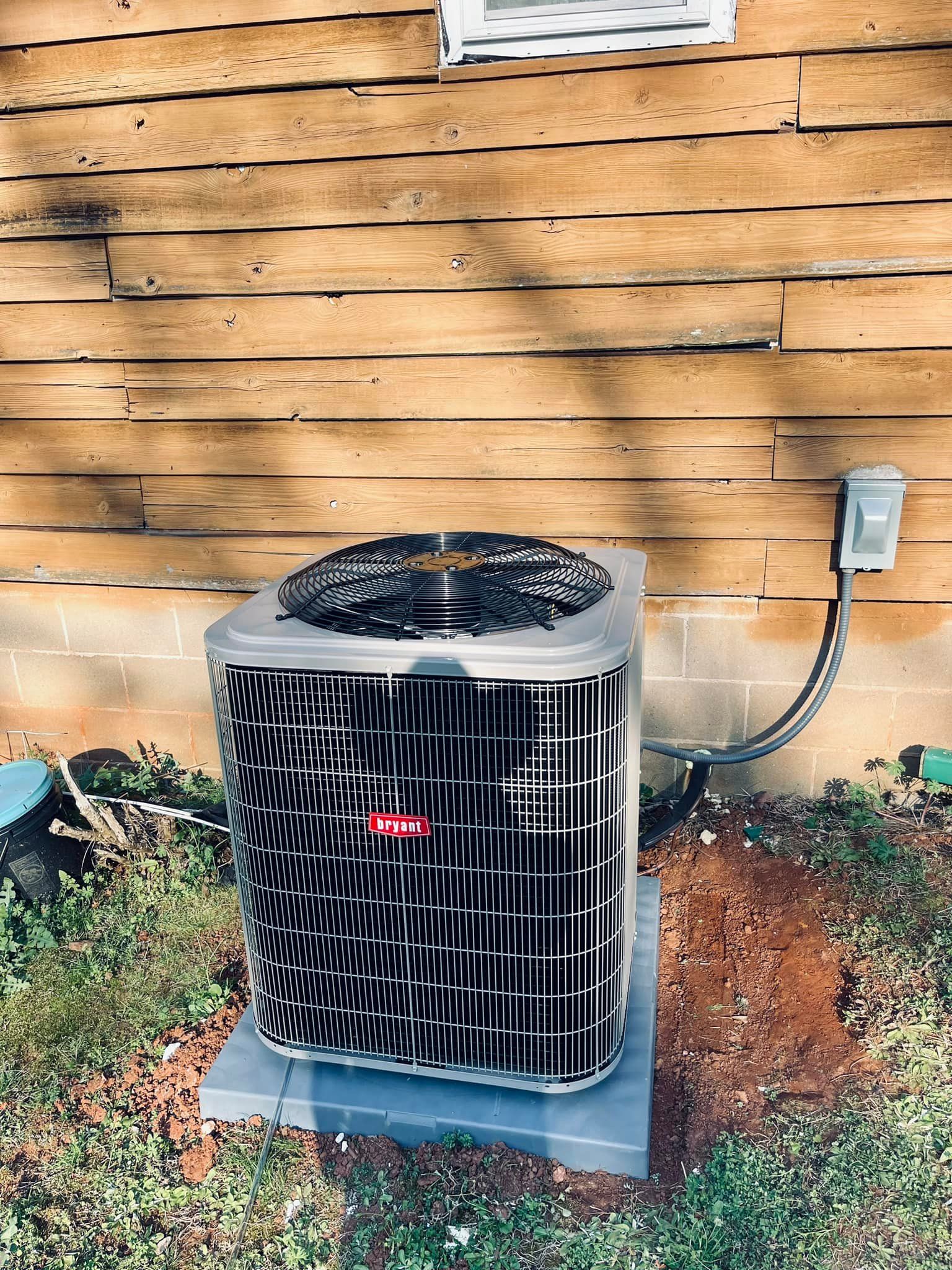 An air conditioner is sitting outside of a wooden house.
