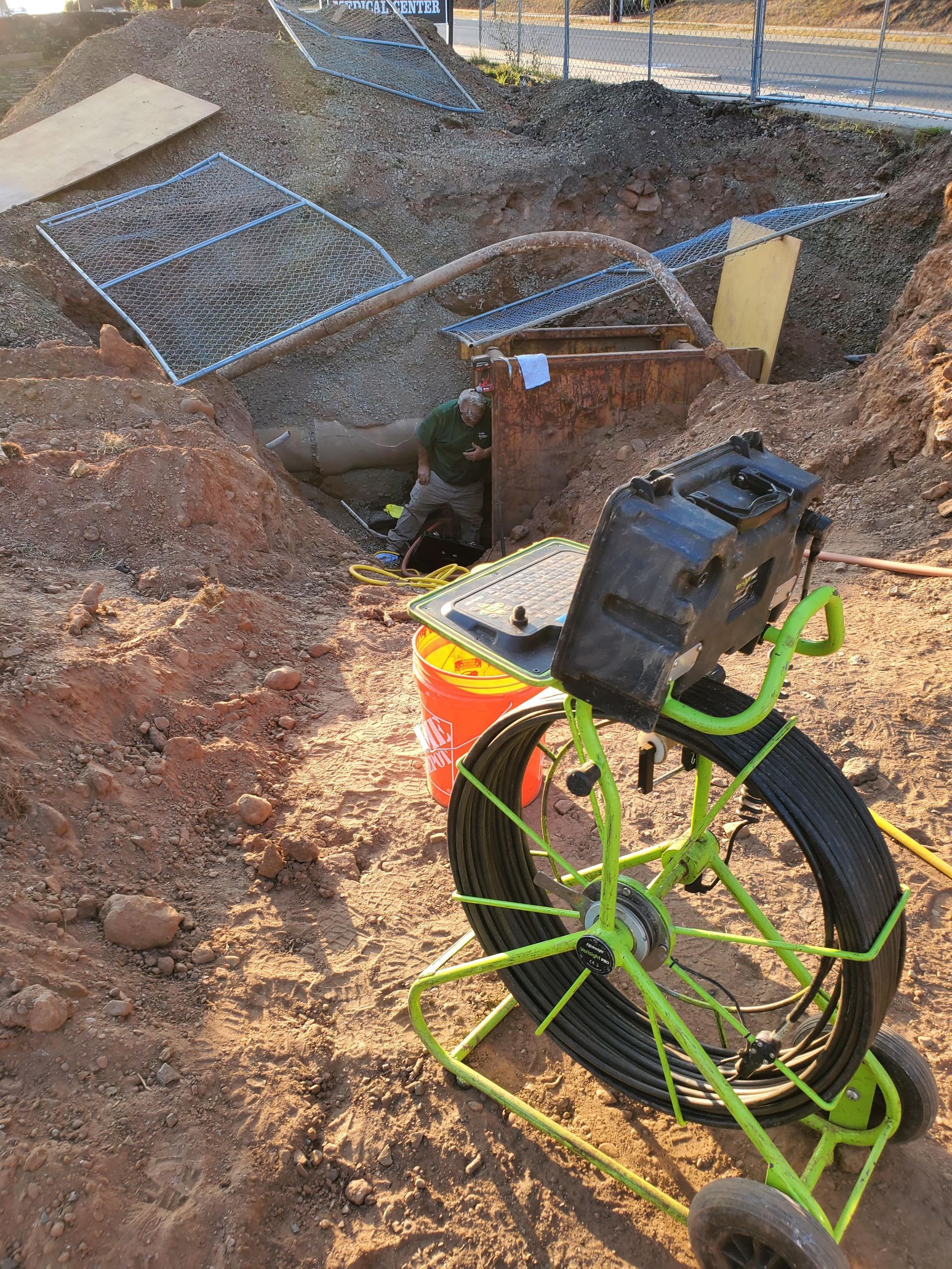A green camera is sitting in the dirt next to a bucket.