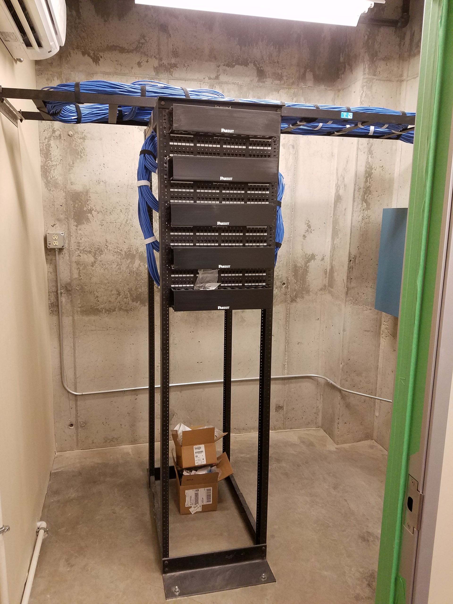 A server rack is sitting in a room next to a green door.