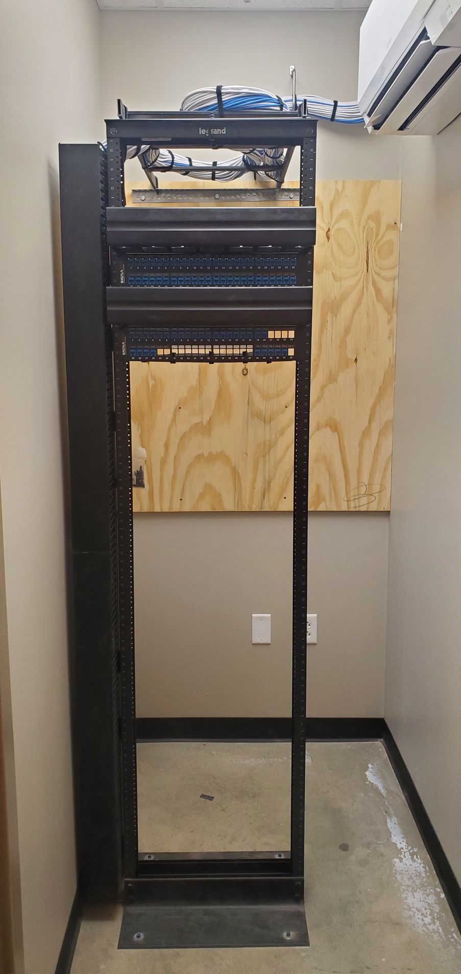 A server rack is sitting in a room next to a wall.