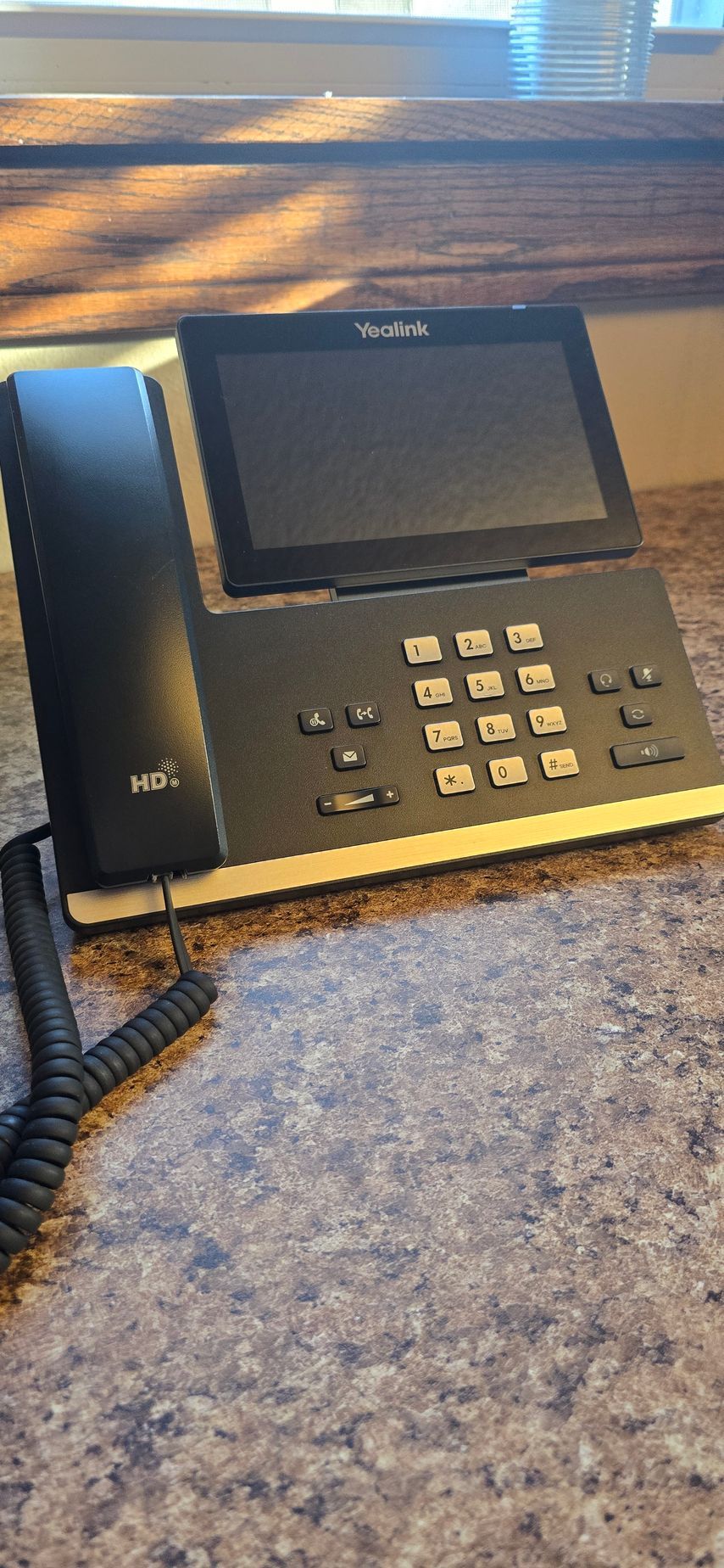 A black telephone with a screen is sitting on a counter.