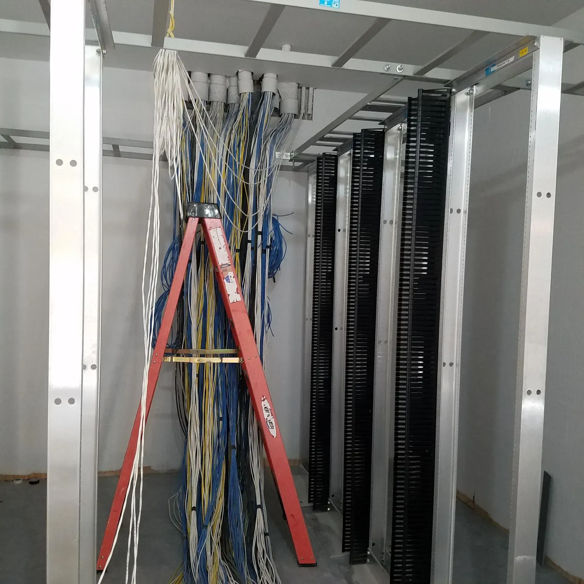 A red ladder is sitting in front of a rack of wires